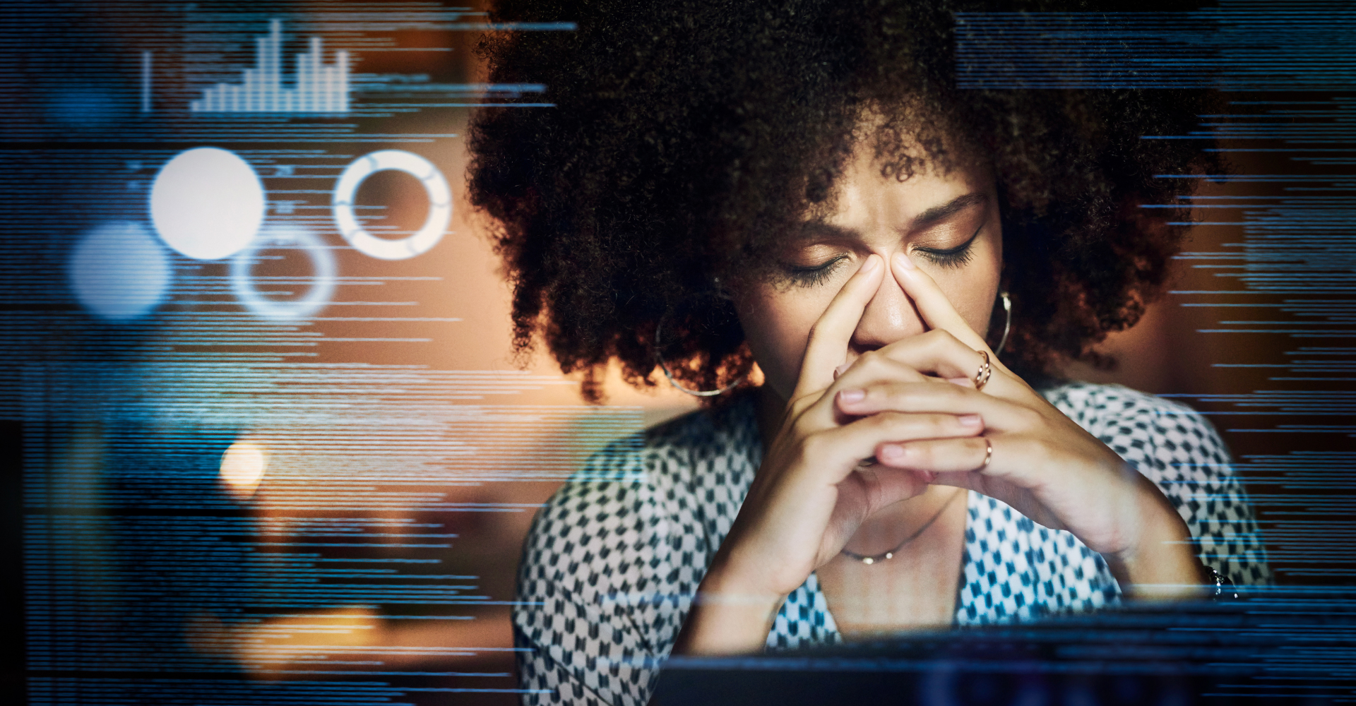 Woman with her hands over her face sat at a computer frustrated by lots of confusing data.